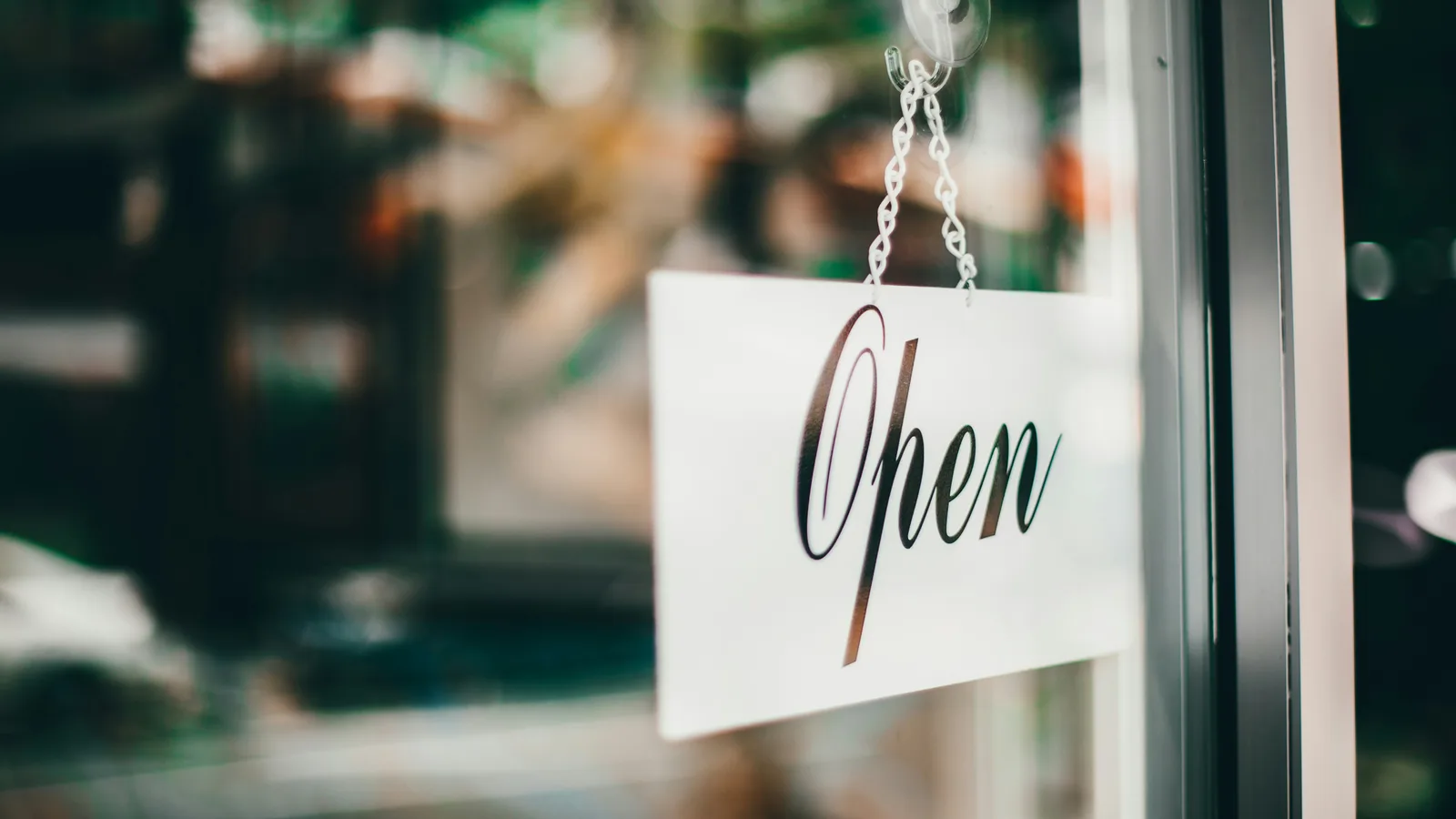 Open sign hanging on the inside of a glass shop door.