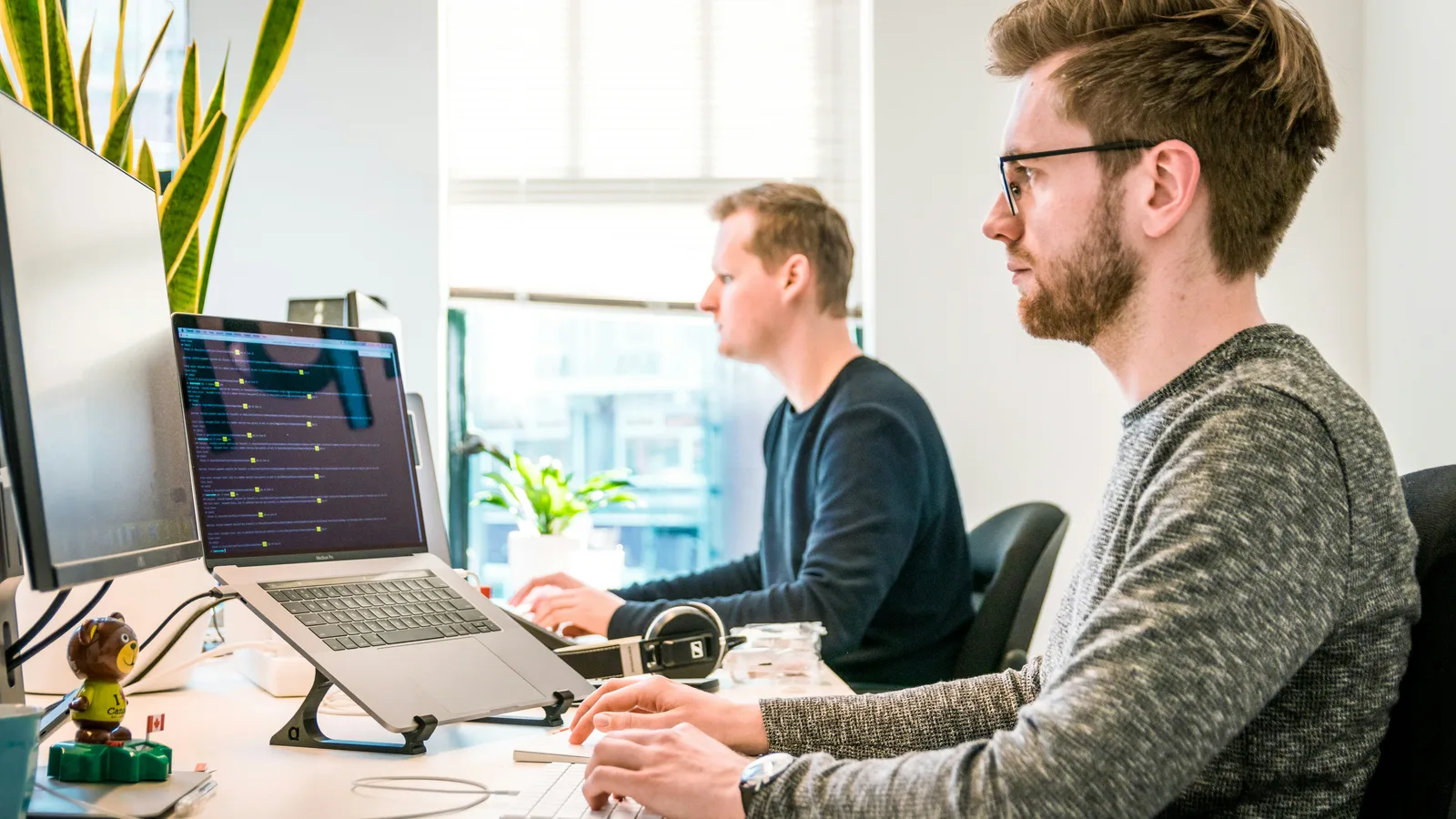 Two people working at computers in a bright office.