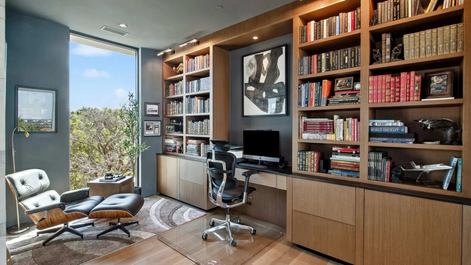 Modern home office with large bookshelves and desk.