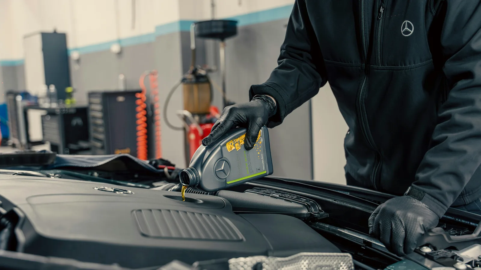 Mechanic pouring oil into car engine.